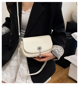 Détail du sac à main crème à texture tressée avec fermoir rotatif argenté et pompon