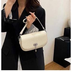 Gros plan du sac beige à texture tressée avec fermoir argenté porté par un mannequin