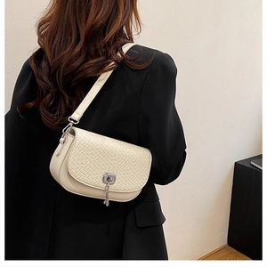 Détail du sac bandoulière tressé crème avec fermoir rotatif argenté et texture en cuir