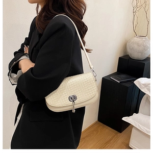 Détail du sac à bandoulière crème tissé avec boucle argentée élégante porté par le modèle