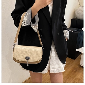 Détail du sac besace beige avec texture tressée et fermoir rotatif en métal argenté
