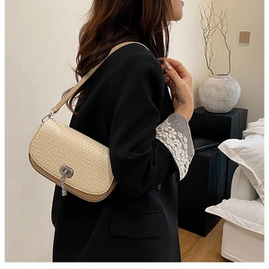 Détail du sac bandoulière beige tissé avec fermoir argenté et glands métalliques sur mannequin