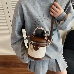 Two-tone woven bucket bag with silk scarf handle and gold hardware on female model