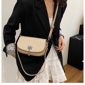 Détail du sac beige à texture tressée avec fermoir chaîne argentée porté par un modèle