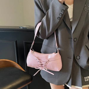 Pink balletcore hobo bag with corset lacing and bow, worn with a grey suit blazer