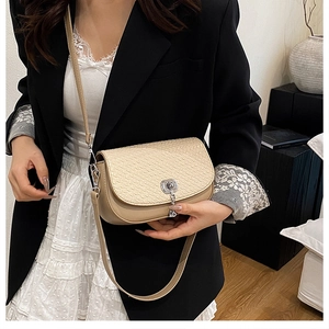 Détail de la texture tressée et du fermoir argenté sur un sac bandoulière beige