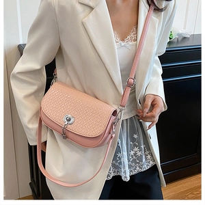 Sac bandoulière rose à texture tissée avec fermoir rotatif argenté sur blazer blanc