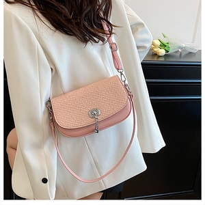 Sac bandoulière rose à texture tressée et fermoir argenté sur un blazer blanc