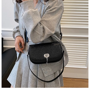 Vue détaillée du sac besace noir tressé avec fermoir rotatif argenté et bandoulière fine