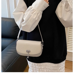 Détail du sac bandoulière crème en cuir tressé avec fermoir rotatif argenté et sangle