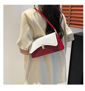 Detail of red and white contrast shoulder bag with gold hardware on a model