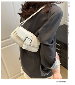 Detail of cream leather shoulder bag featuring a silver buckle and adjustable strap