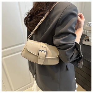 Chic beige baguette bag with oversized buckle detail worn by a model in a minimal setting