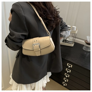 Detail of beige faux leather shoulder bag with large silver buckle on a stylish model