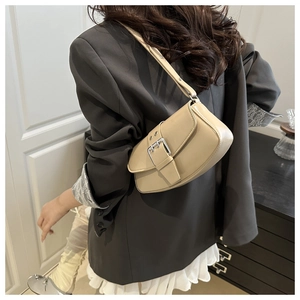 Detail view of beige faux leather underarm bag with silver buckle and adjustable strap