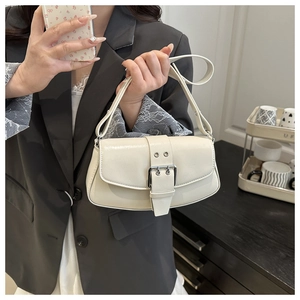 Detail of cream white faux leather baguette bag with silver buckle and eyelet strap
