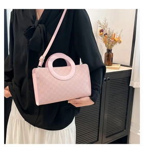 Detail of light pink crossbody bag with circular handle and adjustable shoulder strap