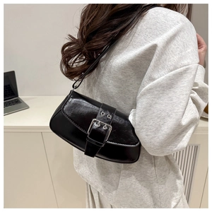 Detail view of a black glossy shoulder bag with vintage silver buckle and punk strap