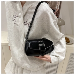 Detail of black patent leather underarm bag with silver buckle in a retro style