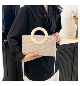 Detail view of monogram M pattern handbag with a unique round white top handle