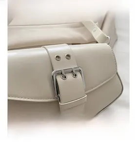 Close-up of beige PU leather shoulder bag with decorative belt strap and silver buckle