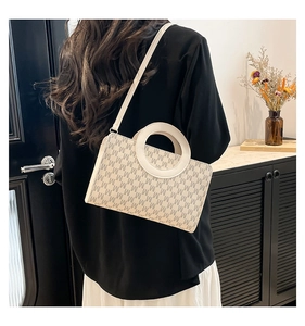 Model wearing a minimalist cream crossbody bag with grey M pattern in a modern interior