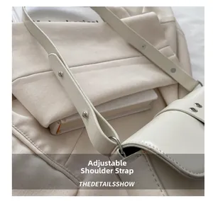 Detailed view of the adjustable cream PU leather shoulder strap with silver metal buckle