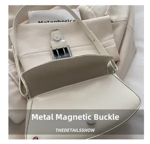Close-up of cream leather saddle bag showing metallic magnetic buckle and texture