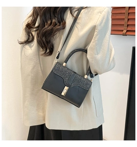 Detail of black leather handbag with sparkling sequin flap and gold metallic lock closure