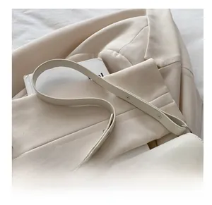 Close-up of a creamy white glossy leather bag featuring large silver double-pin buckles