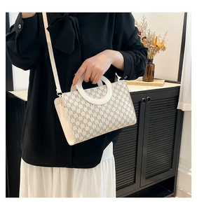 Detail of white leather crossbody bag with M-pattern and unique round ring handle