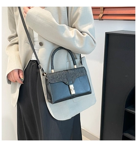 Detail of black leather crossbody bag with sequined flap and metallic turn-lock closure