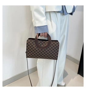 Close-up of brown M-letter monogram handbag with unique round handle and strap