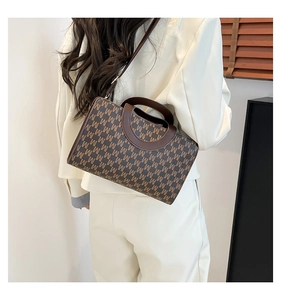 Detailed side view of a brown patterned crossbody bag worn with a white blazer