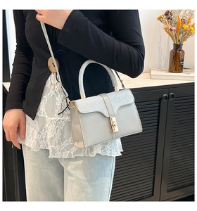 Detail of silver sequined handbag with gold metallic twist lock and smooth leather
