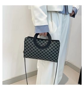 Detail of vintage square handbag with M-pattern monogram and unique round leather handle