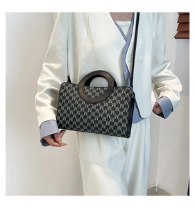Detail of grey monogram letter pattern and leather texture on a stylish handbag