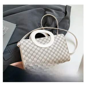 Macro detail of the cream retro handbag featuring a stylish M-letter print and ring handle