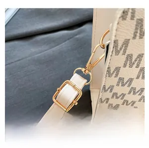 Detail of adjustable shoulder strap and golden metal hooks on beige monogram crossbody bag