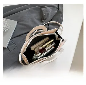 Top view of spacious interior of cream leather bag holding phone and cosmetics