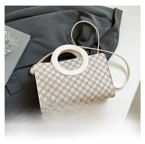 Detailed size comparison of the monogrammed crossbody bag next to a smartphone