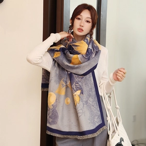 Detailed close-up of blue and yellow floral pattern scarf with soft fringe trim texture