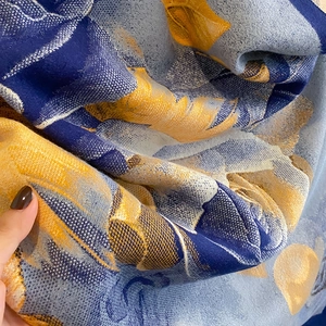 Close-up of winter scarf with blue and yellow floral print showing knit texture