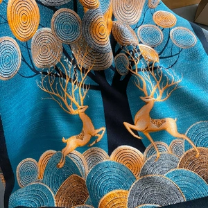 Gros plan sur le motif jacquard renne doré de l'écharpe en cachemire bleu doux