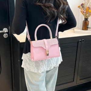 Pink fashion handbag with glitter details and gold hardware, worn as a crossbody bag