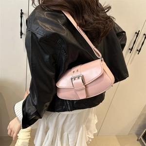 Minimalist pink underarm bag with silver buckle worn by a model in a stylish leather jacket