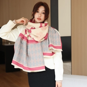 Close-up of thick knit shawl with pink floral patterns and fringe detail