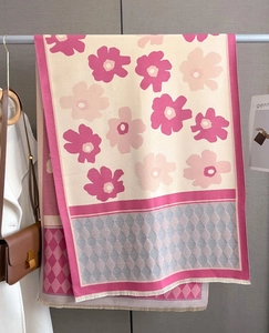 Detailed view of pink floral pattern and diamond lattice on a cashmere scarf