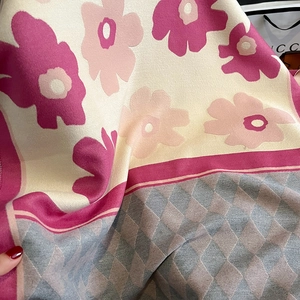 Detail of soft cashmere-feel scarf showing pink floral patterns and grey diamond weave texture