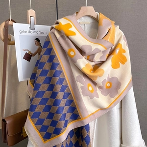 Detail of floral and argyle knit scarf with fringe trim on a white coat